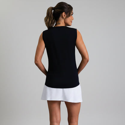 Back view of a woman wearing a black sleeveless muscle tank and white skirt on a gray background