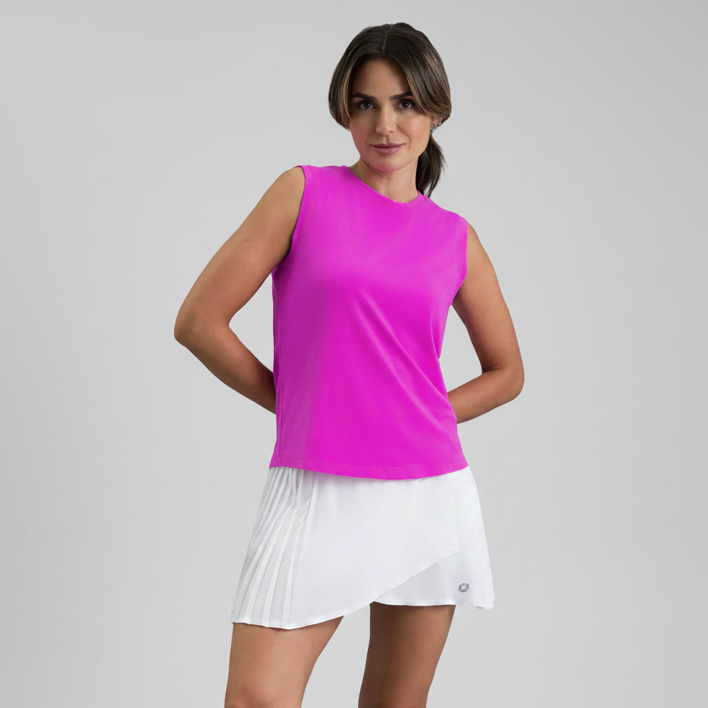 Woman wearing a pink sleeveless muscle tank and white skirt on a gray background