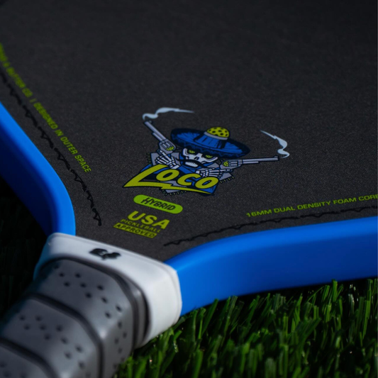 Close-up of a Bread & Butter Loco 16mm Hybrid pickleball paddle – carbon fiber face, USAP approved paddle with 'Loco' branding on a grass surfaced 