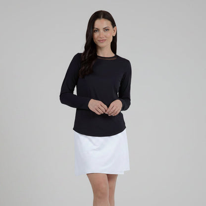 Woman wearing a black top and white tennis skirt on a gray background