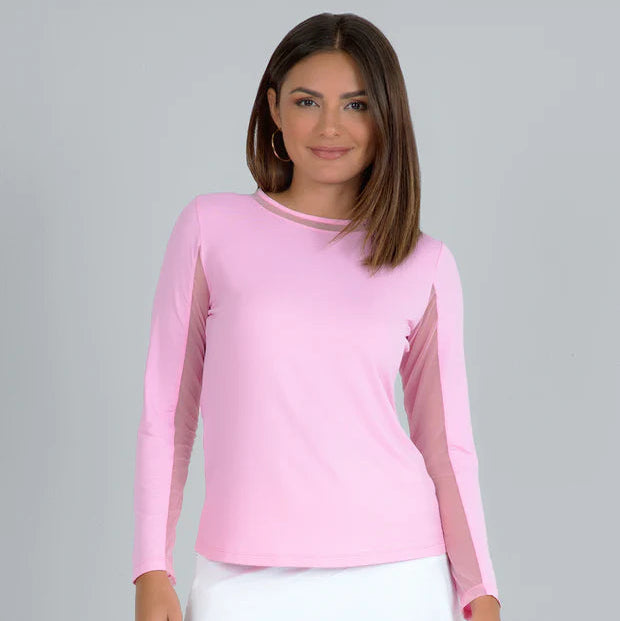 Woman wearing a pink long-sleeve top with sheer sleeves and a white skirt on a gray background