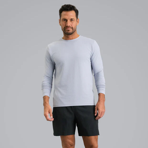 Man wearing a light gray long-sleeve UV 50+ sun protection shirt and black shorts on a gray background
