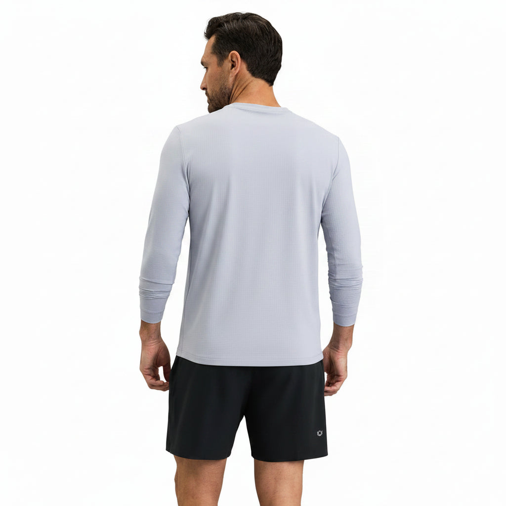 Man wearing a light gray long-sleeve shirt and black shorts on a gray background