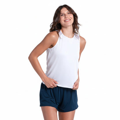 Woman wearing a white sleeveless loose fitting tank and navy shorts on a white background