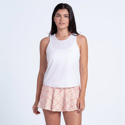 Woman wearing a white sleeveless top and pink checkered shorts on a light gray background