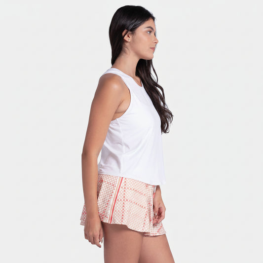 Woman wearing a white sleeveless top and red patterned shorts on a light gray background