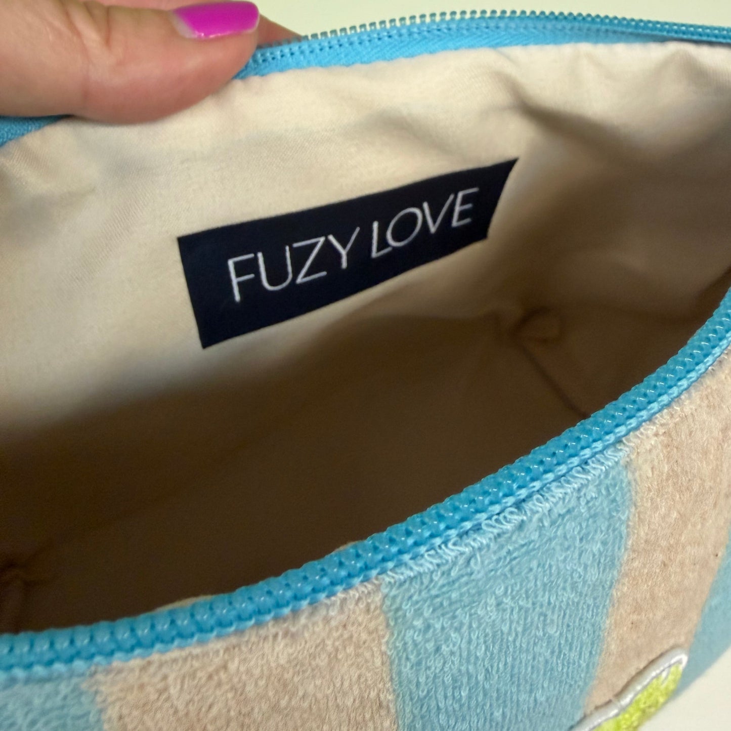 Close-up of a product with 'FUZY LOVE' label held by a hand against a light background
