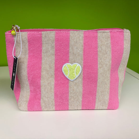 Pink and beige striped pouch with a heart-shaped tag on a white surface with a green background