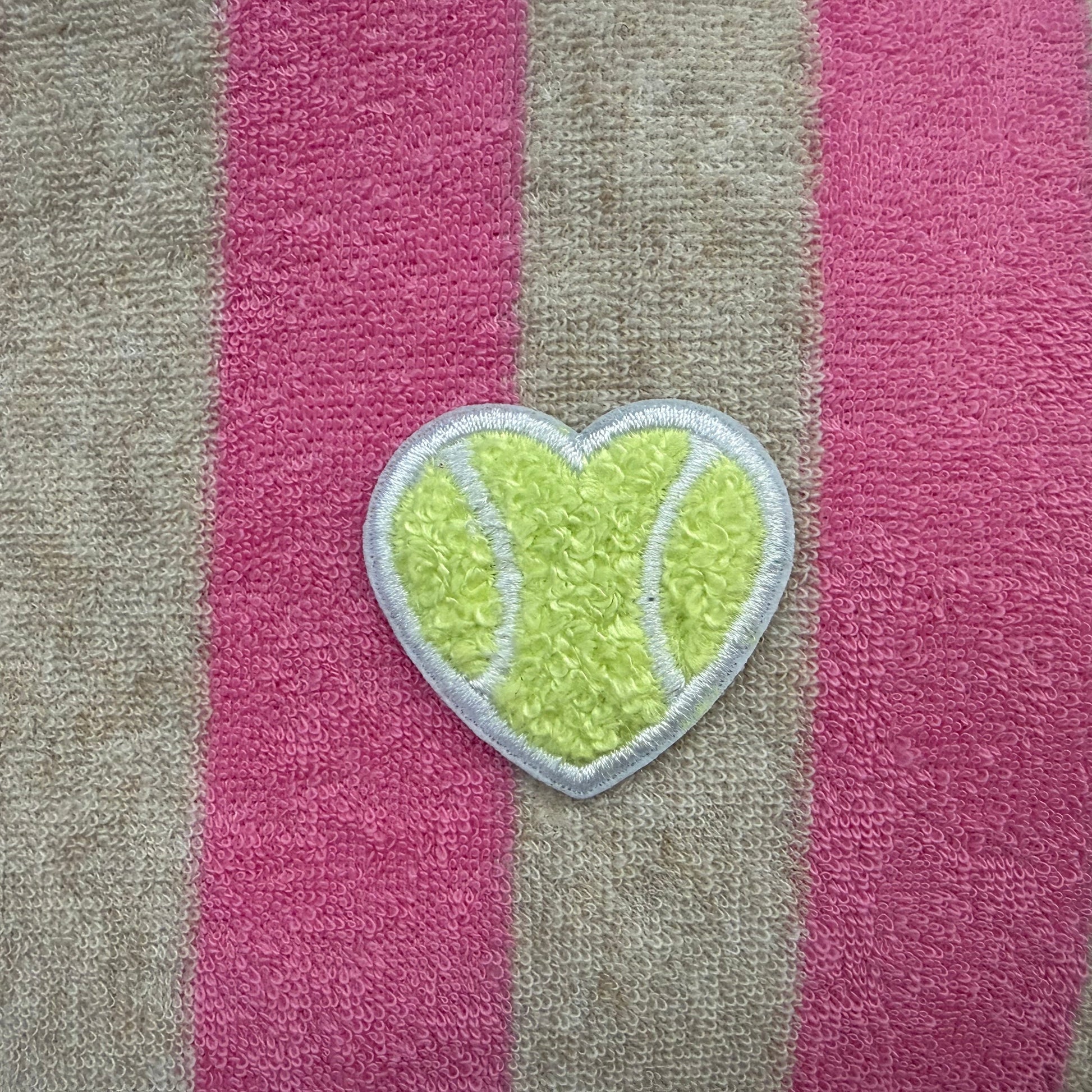 Striped towel with a heart-shaped green patch on a pink and gray background