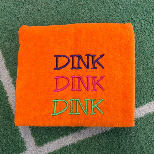 Orange towel embroidered with three stacked DINK words in purple, pink, and green