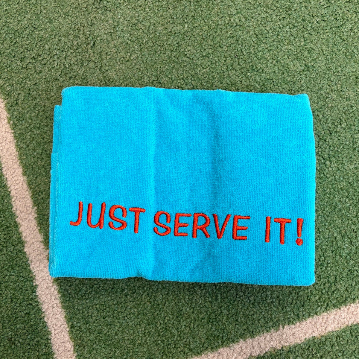 Aqua towel embroidered with orange JUST SERVE IT lettering