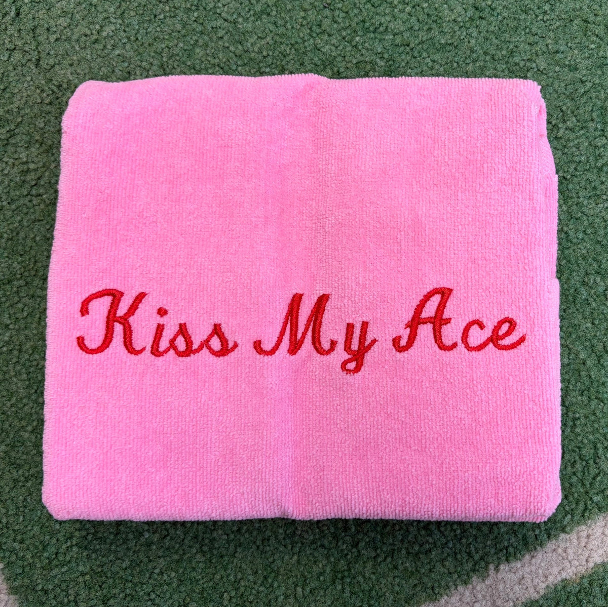 Light pink towel embroidered with red Kiss My Ace lettering