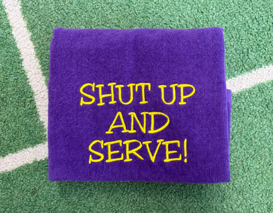 Purple towel embroidered with yellow SHUT UP AND SERVE lettering