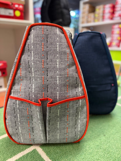 Ollie and Nell tennis backpack in Orange / Black, showing the woven-look front and contrasting orange trim