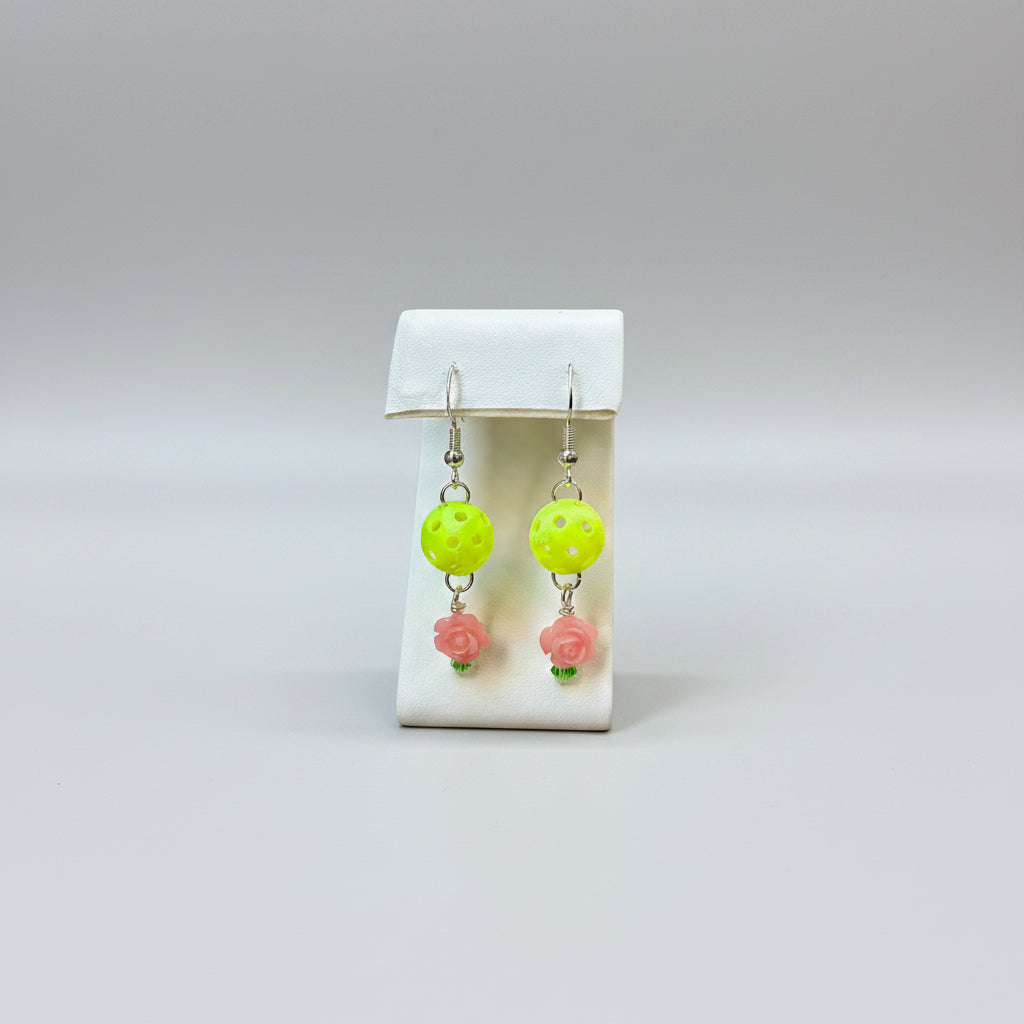 Pair of mini pickleball earrings on a display stand with a soft grey background.