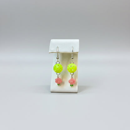 Pair of mini pickleball earrings on a display stand with a soft grey background.
