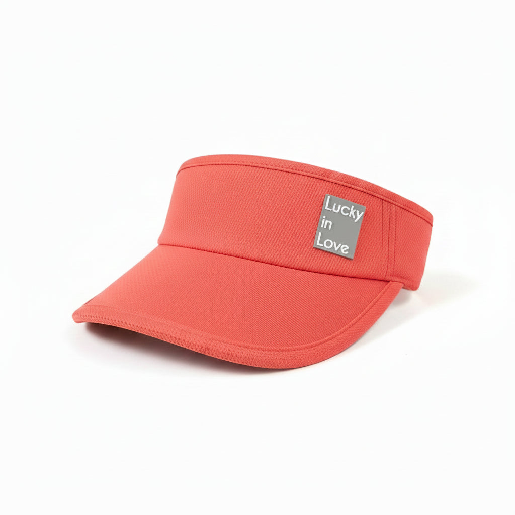 Coral visor with a Lucky In Love brand label on a white shelf