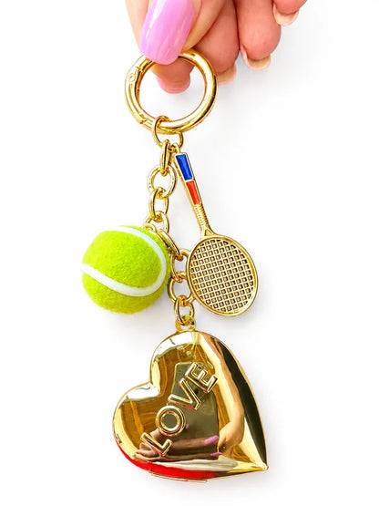 Fuzy Love LOVE heart locket keychain with tennis ball and racquet charms on white background
