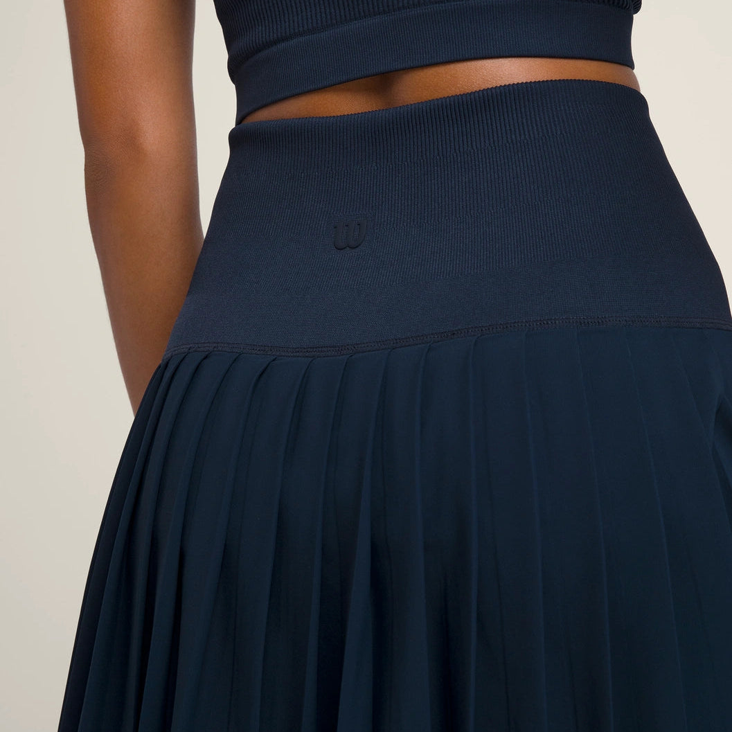 Navy blue tennis skort skirt worn by a person on a beige background