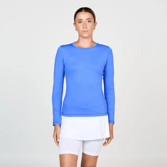 Woman wearing a blue long-sleeve top and white shorts on a light gray background